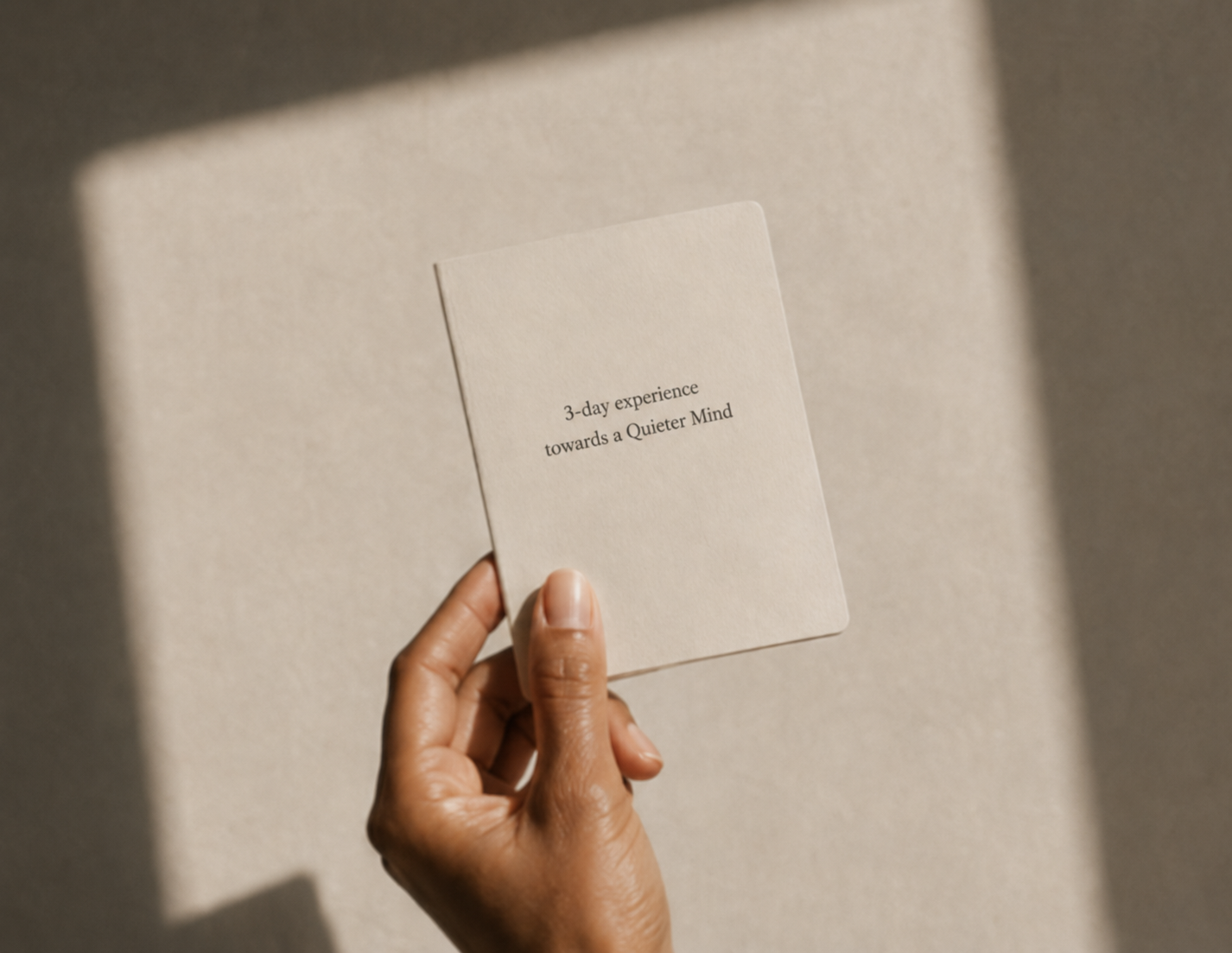 A hand holding a small cream card reading 3-day experience towards a Quieter Mind